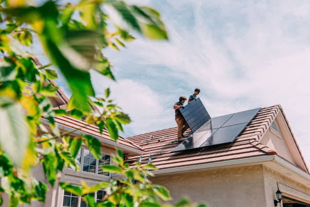 Low Angle view of Two Caucasian Male Homeowners or DIY-ers installing Solar Panels to Brackets on a Suburban Home with Clay Tiles in the Summer